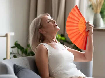 Una mujer pasando calor se abanica Una mujer pasando calor se abanica