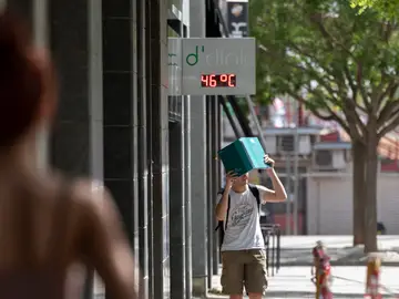 Un joven camina por una calle de Lleida, bajo un termómetro que indica los 47ºC este miércoles.