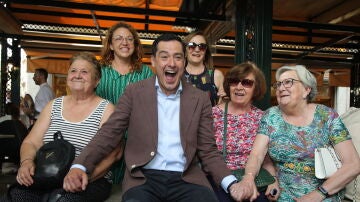 El candidato del PP a la reelección en la Junta, Juanma Moreno, bromea con un grupo de mujeres durante un paseo realizado hoy miércoles por Granada cuando se celebran las fiestas del Corpus.