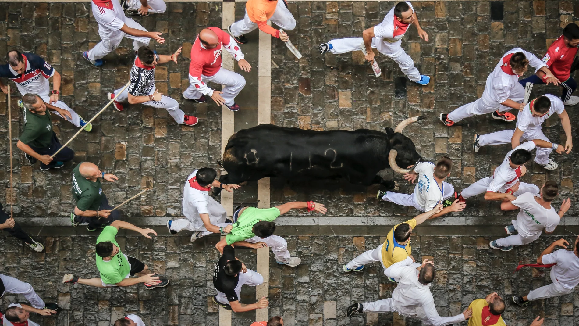 Varios corredores participan en el encierro de San Fermín, corriendo junto a los toros.