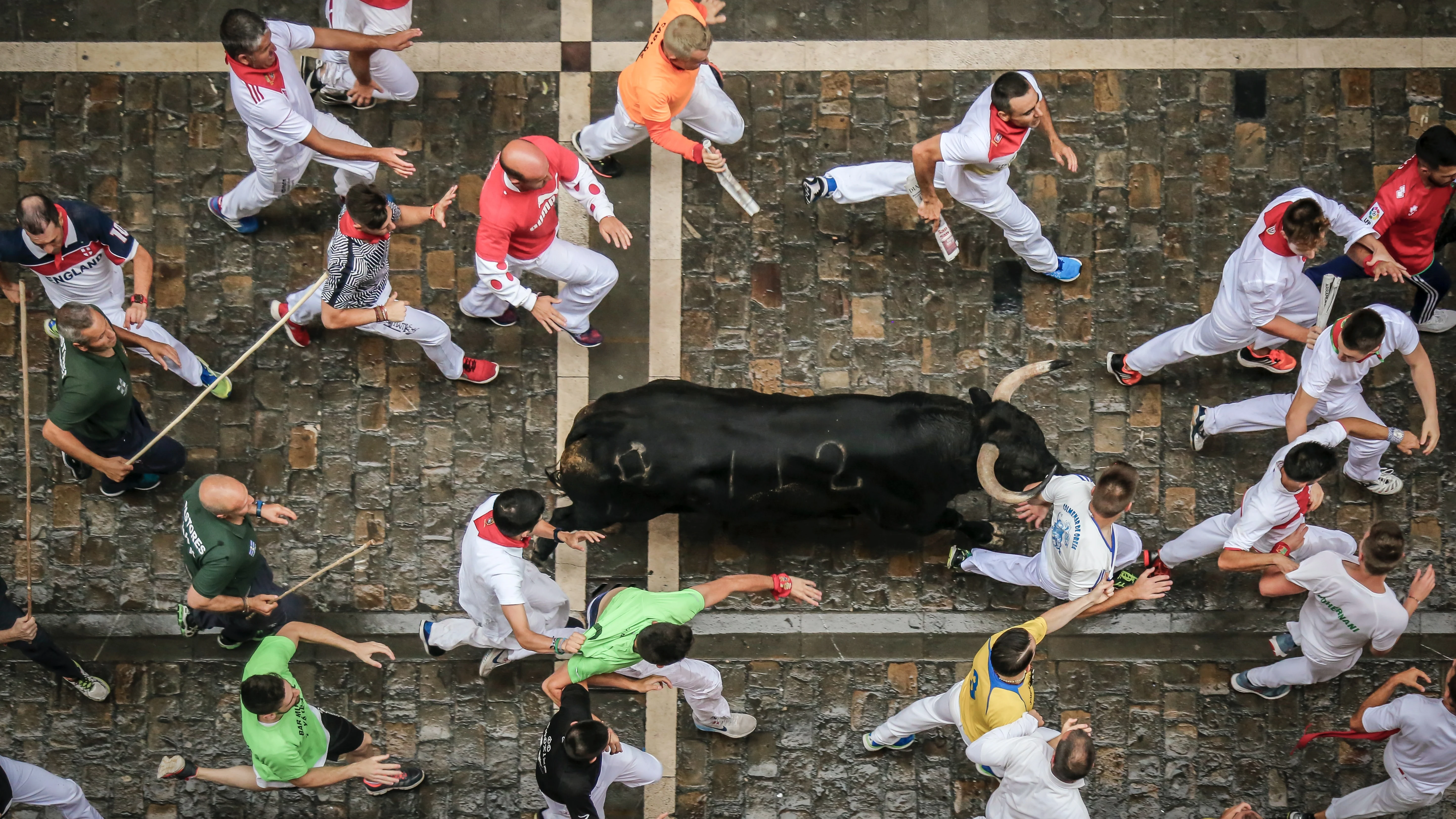 Varios corredores participan en el encierro de San Fermín, corriendo junto a los toros.