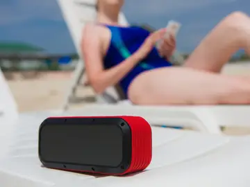 Chica en la playa escuchando música con un altavoz