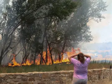 Una mujer observa las llamas del incendio forestal registrado en la comarca de Tábara (Zamora)