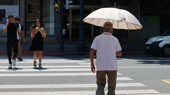 Un hombre se protege del calor con un paraguas. Un hombre se protege del calor con un paraguas.
