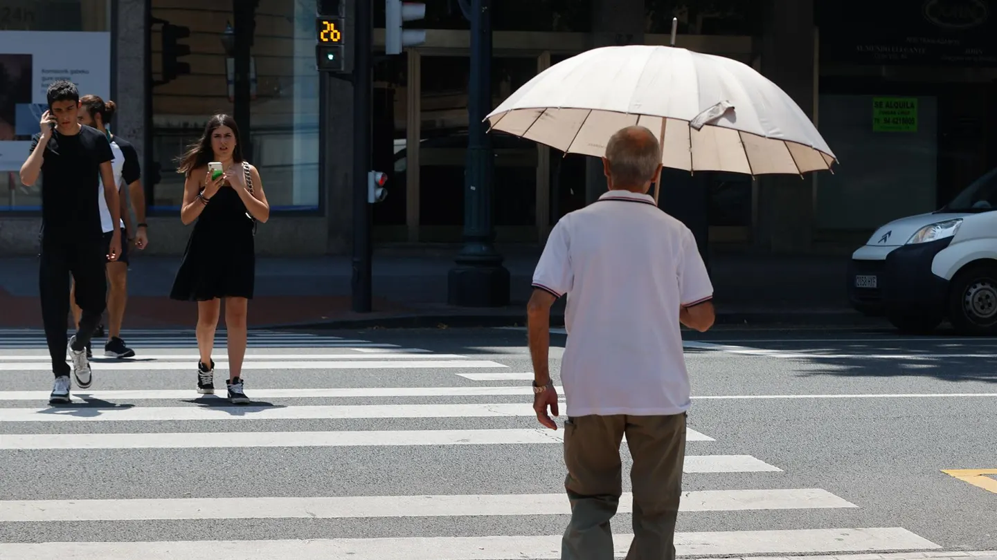 Un hombre se protege del calor con un paraguas. Un hombre se protege del calor con un paraguas.