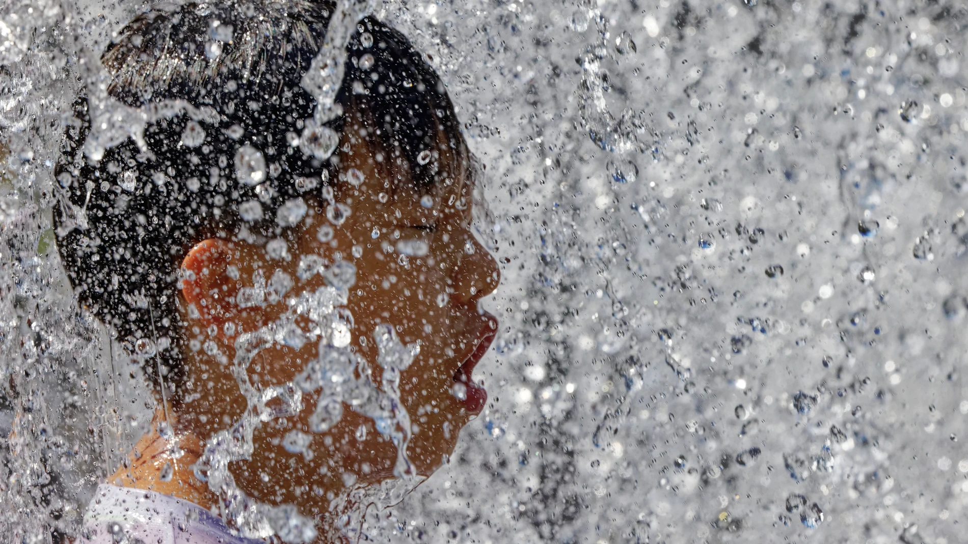 Una persona se refresca en una fuente frente al calor