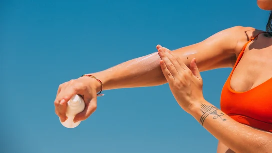 Una mujer, echándose protector solar Una mujer, echándose protector solar