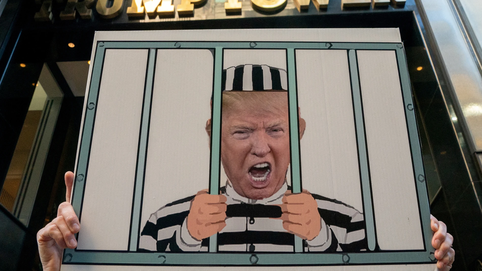 Un manifestante porta una pancarta de Trump 'en la cárcel' frente a la Trump Tower de Nueva York