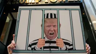 Un manifestante porta una pancarta de Trump 'en la cárcel' frente a la Trump Tower de Nueva York