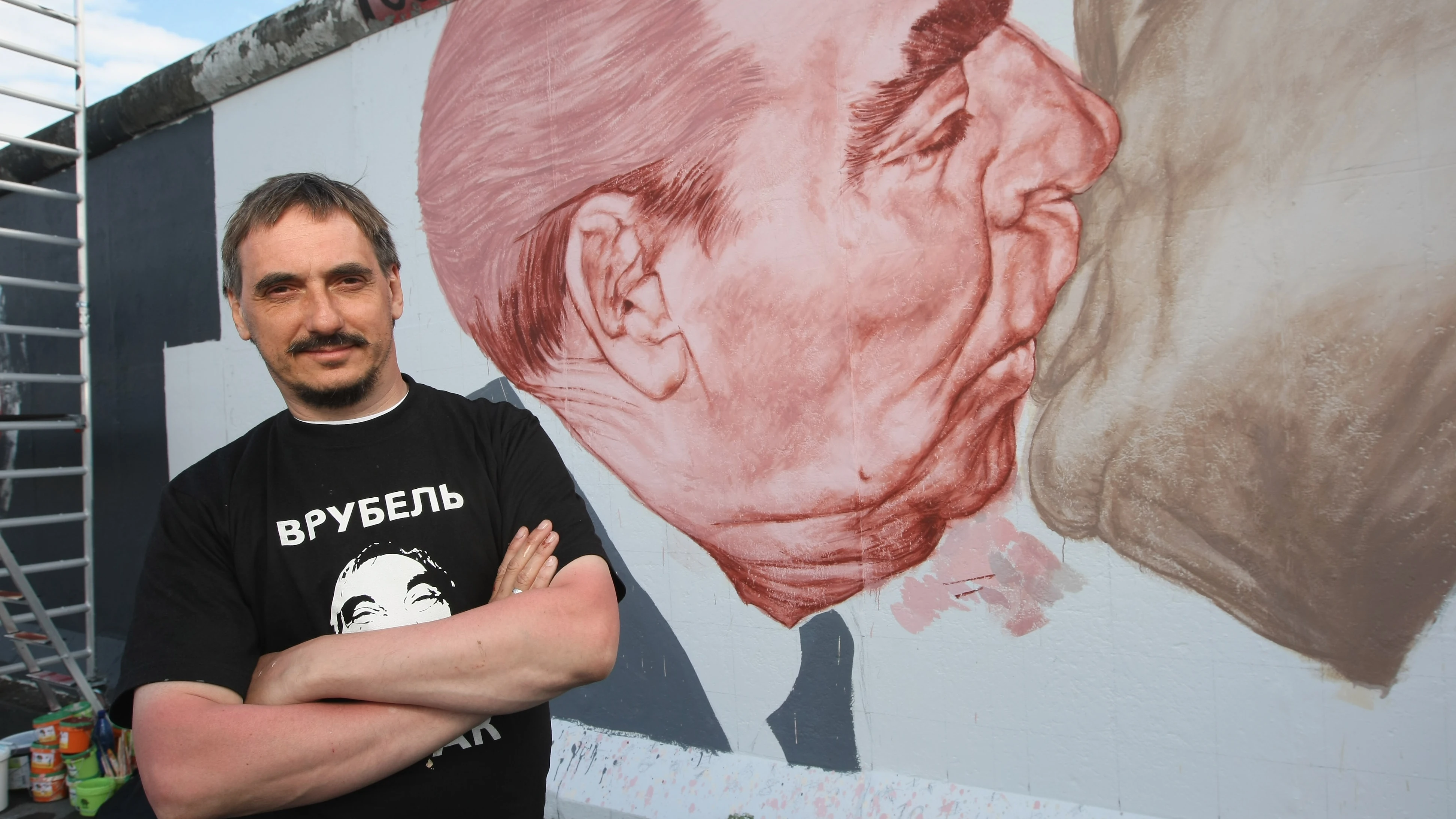 El artista ruso Dmitri Vrúbel, frente al Beso del Muro de Berlín.