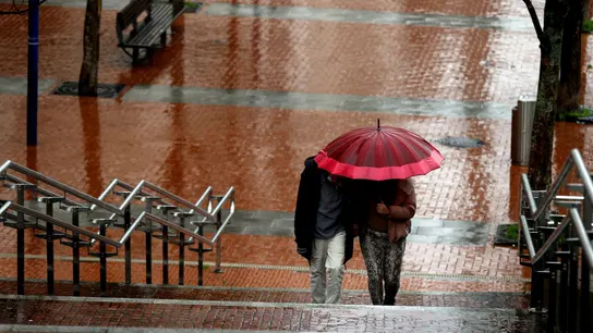 Dos personas pasean protegiéndose de la lluvia. Fin de la ola de calor: las lluvias y tormentas ponen en alerta a seis comunidades autónomas