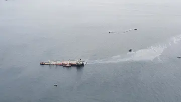 Imagen aérea del buque con la mancha de fuel que sale de la barrera