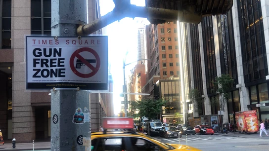 Un taxi pasa delante de un letrero con el mensaje "Times Square, zona libre de armas". Un taxi pasa delante de un letrero con el mensaje "Times Square, zona libre de armas".