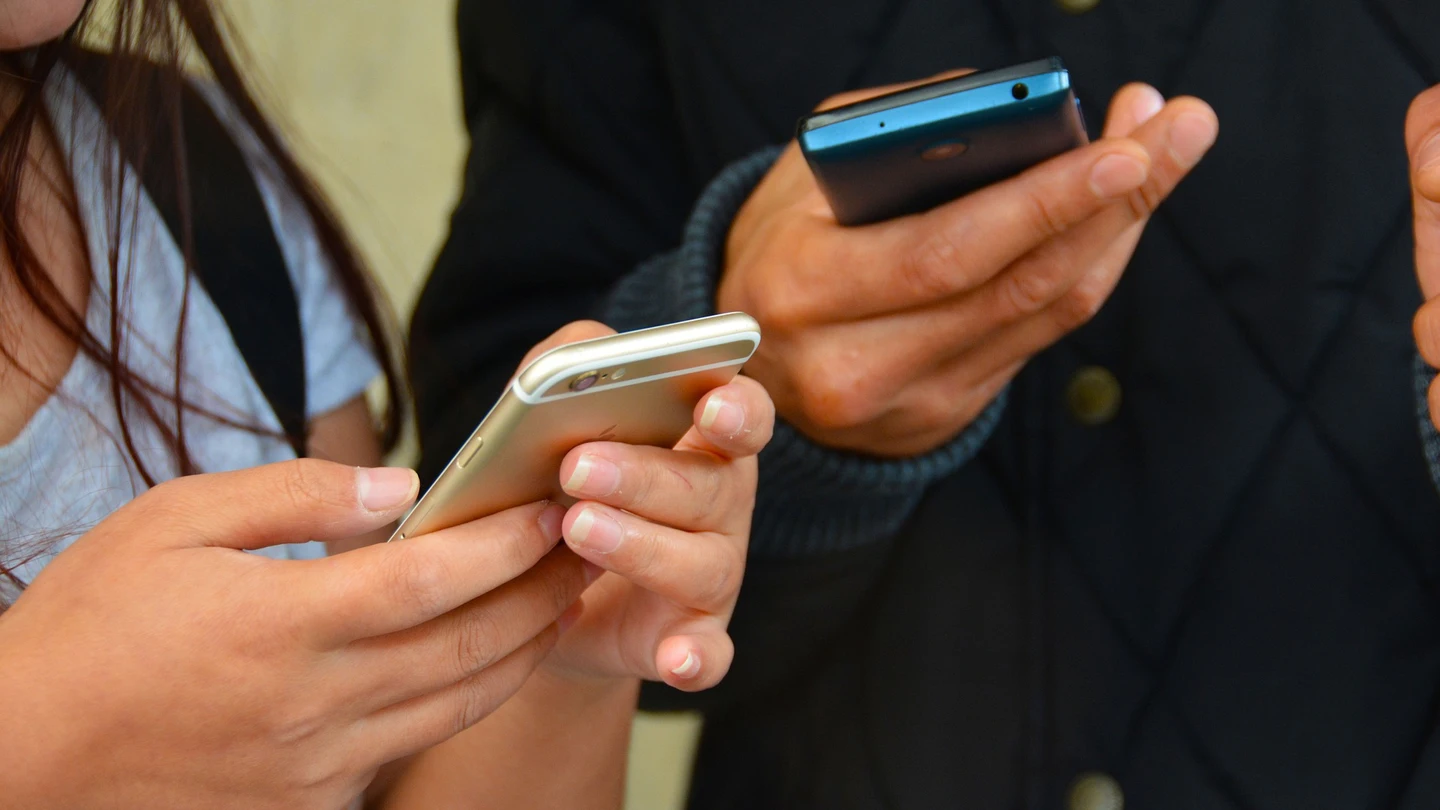 Dos adolescentes utilizan sus teléfonos en una imagen de archivo Dos adolescentes utilizan sus teléfonos en una imagen de archivo