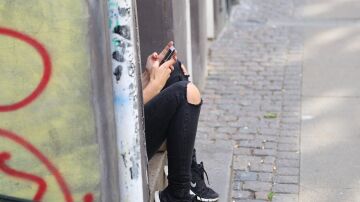 Una adolescente mira su teléfono móvil