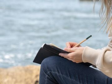 Una mujer rubia, escribiendo junto al mar
