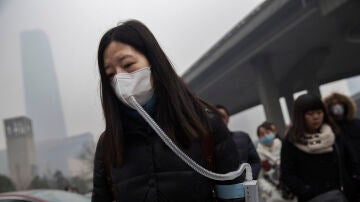 Una mujer usa una mascarilla para poder respirar por la fuerte contaminación en Pekín