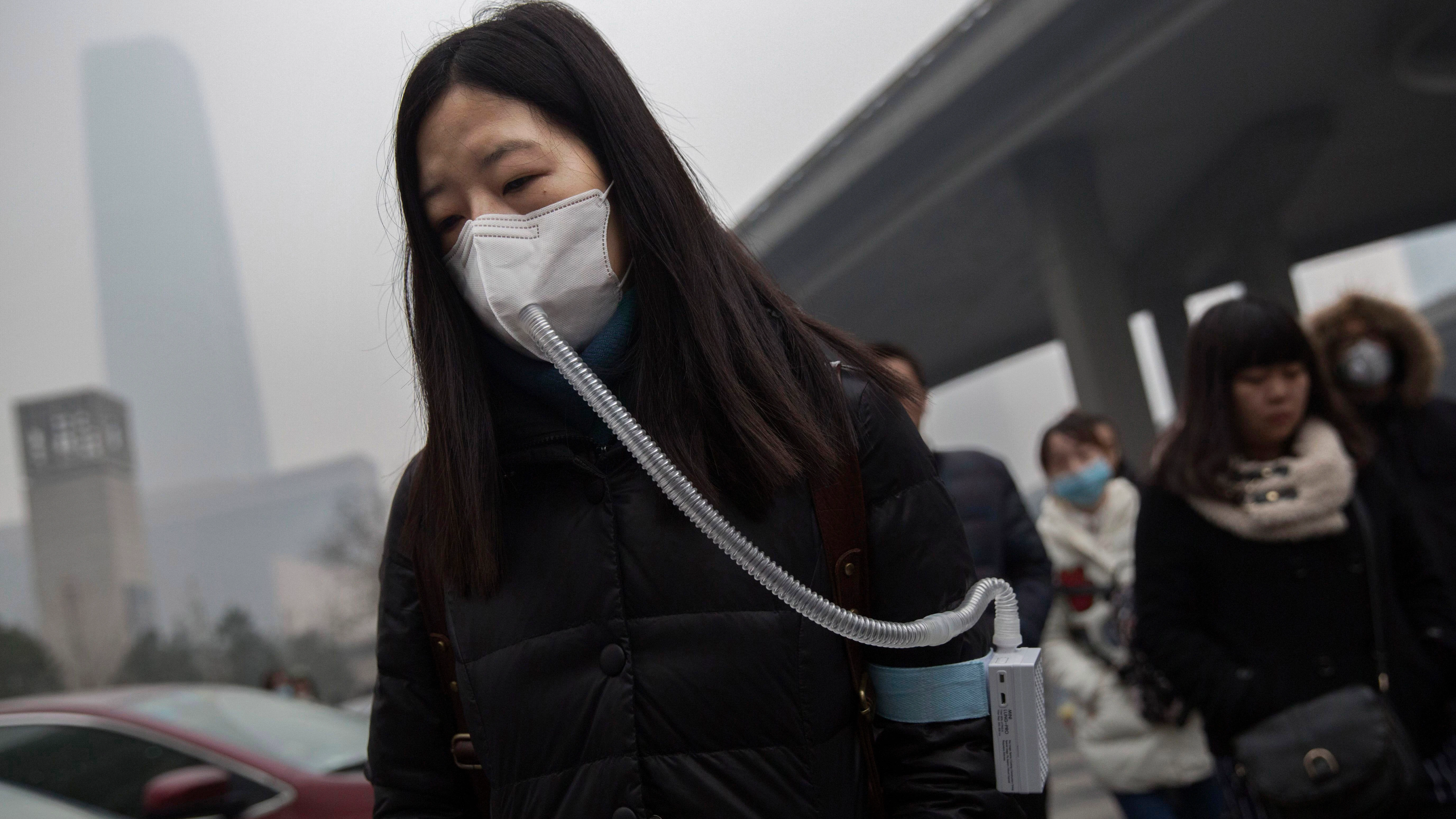 Una mujer usa una mascarilla para poder respirar por la fuerte contaminación en Pekín