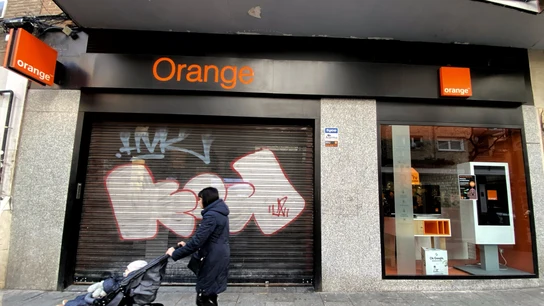 Una mujer pasea frente a una tienda de de la compañía telefónica Orange Una mujer pasea frente a una tienda de de la compañía telefónica Orange