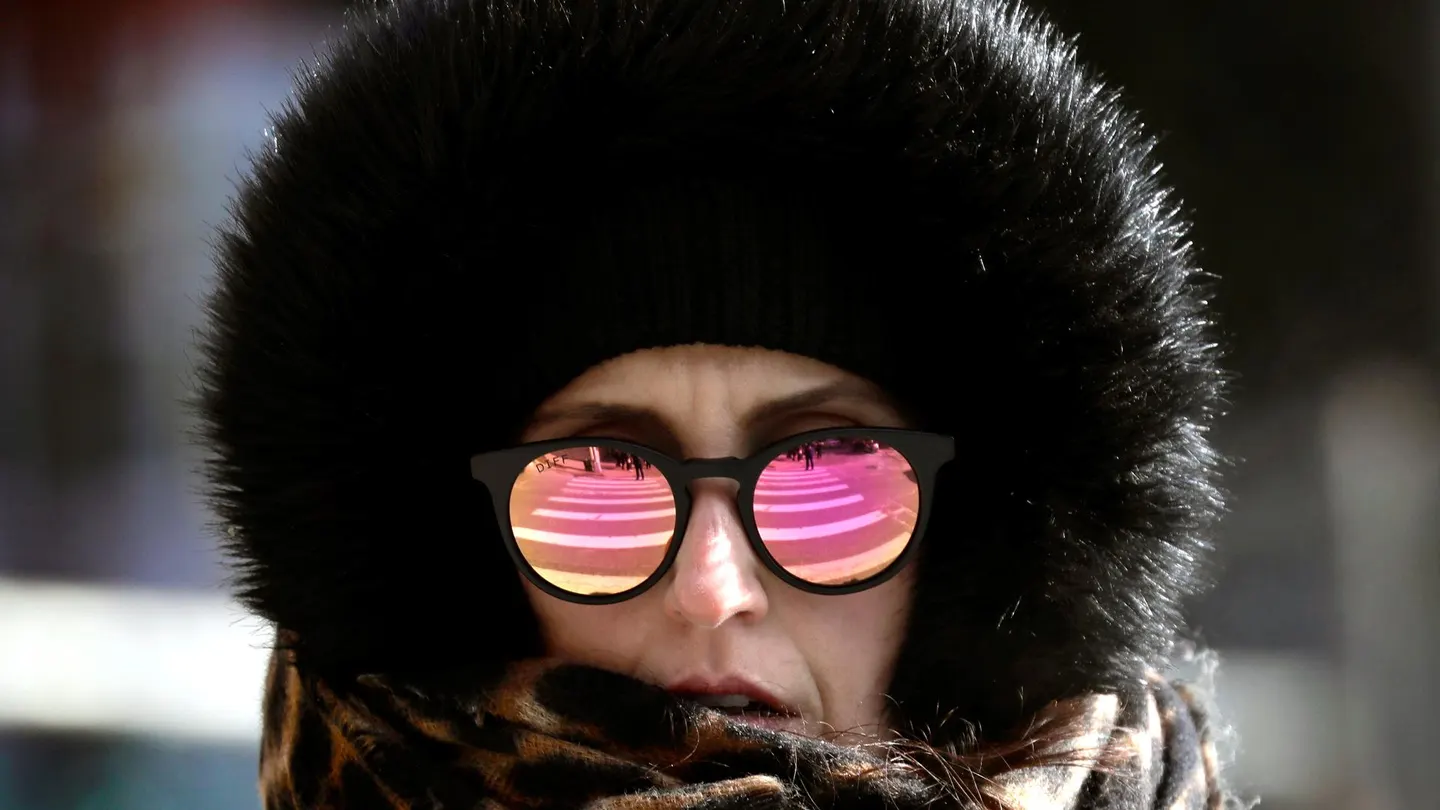 Una mujer con bufanda, capucha y gafas de sol, en una fotografía de archivo Una mujer con bufanda, capucha y gafas de sol, en una fotografía de archivo