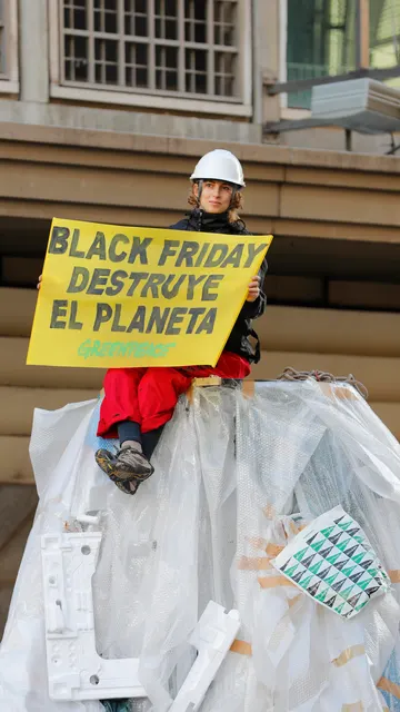 Una activista de Greenpeace subida a un montón de plástico de embalaje.
