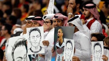 Aficionados qataríes, con imágenes de Özil mientras se tapan la boca