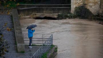 Una persona fotografía el río Guadalquivir tras las intensas lluvias en Córdoba