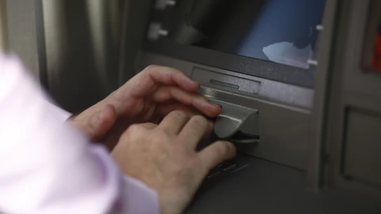 Imagen de una persona operando en un cajero automático. Imagen de una persona operando en un cajero automático.