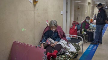 Una paciente recibe un goteo intravenoso mientras usa una mascarilla de oxígeno en la sala de Urgencias de un hospital en Pekín