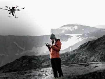 Joven volando un dron en una pista de esquí