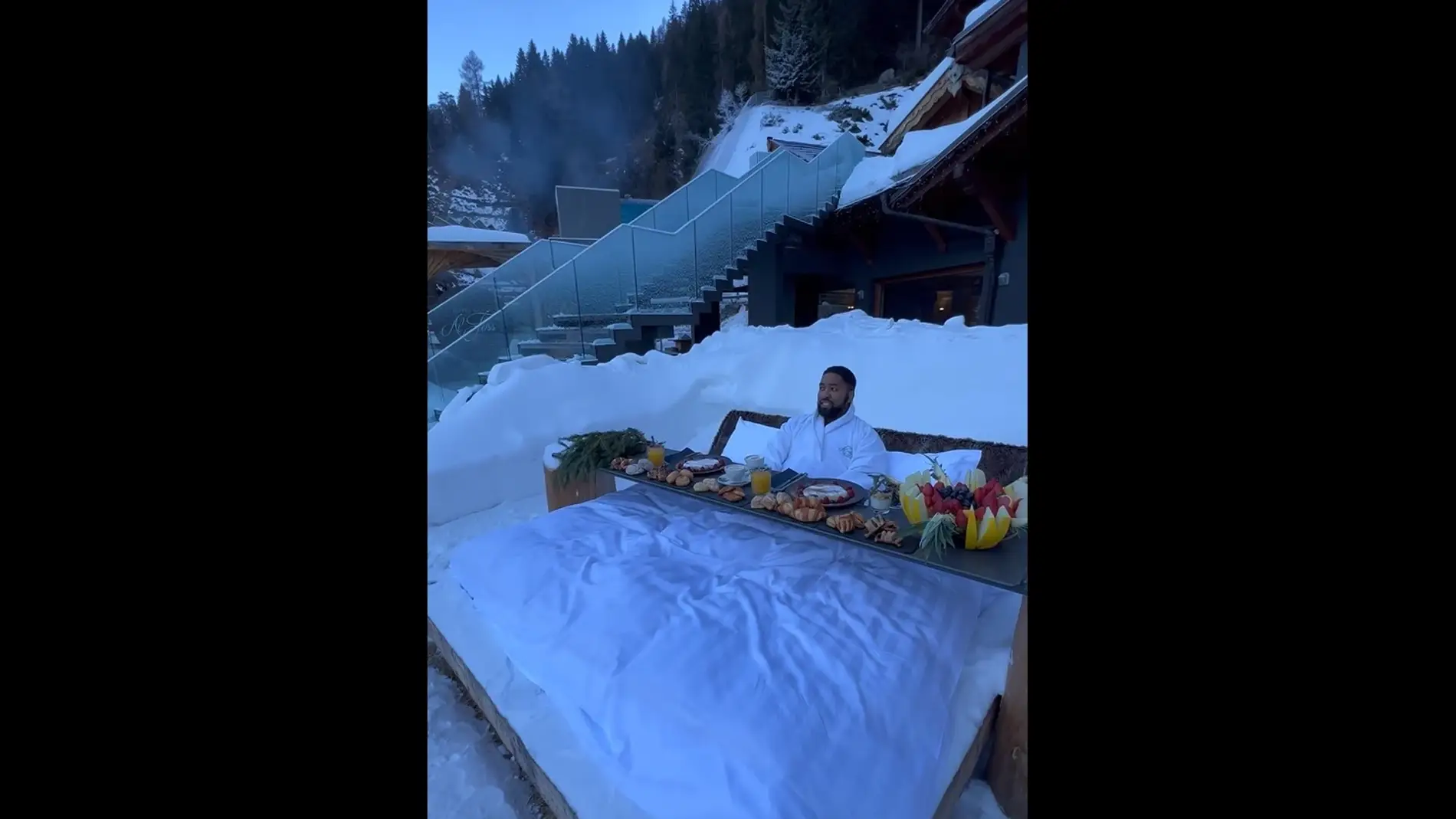 Hombre desayunando en una cama en la nieve