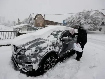 Una persona limpia su coche bajo la nieve en enero de 2023