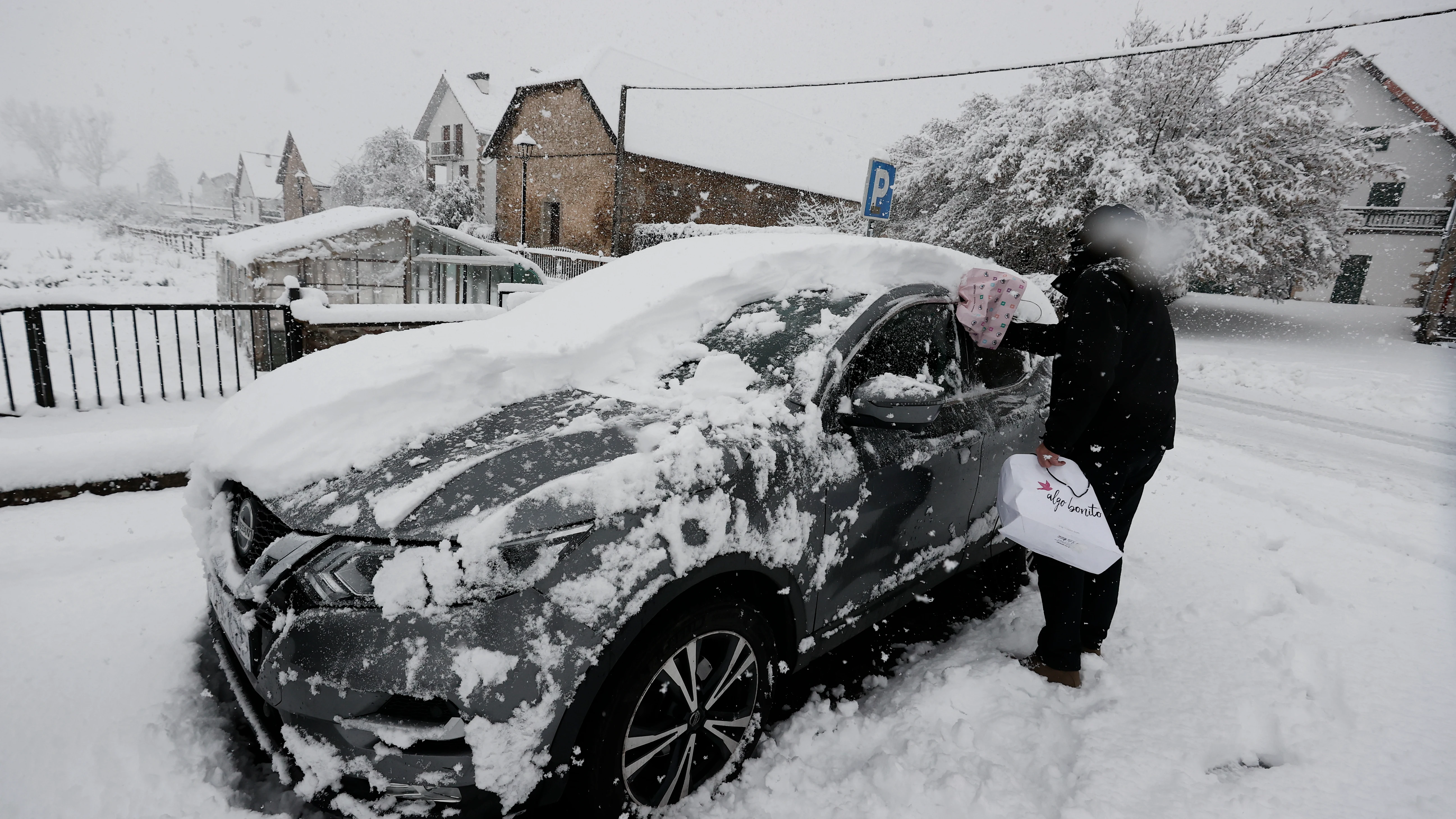 Una persona limpia su coche bajo la nieve en enero de 2023