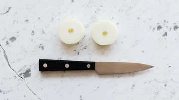 Un cuchillo junto a dos trozos de cebolla cortada