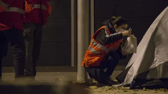 Una trabajadora social de Cruz Roja entrega una bolsa de comida a una persona sin hogar Una trabajadora social de Cruz Roja entrega una bolsa de comida a una persona sin hogar
