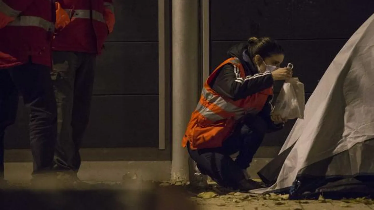 Una trabajadora social de Cruz Roja entrega una bolsa de comida a una persona sin hogar Una trabajadora social de Cruz Roja entrega una bolsa de comida a una persona sin hogar