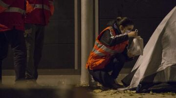 Una trabajadora social de Cruz Roja entrega una bolsa de comida a una persona sin hogar