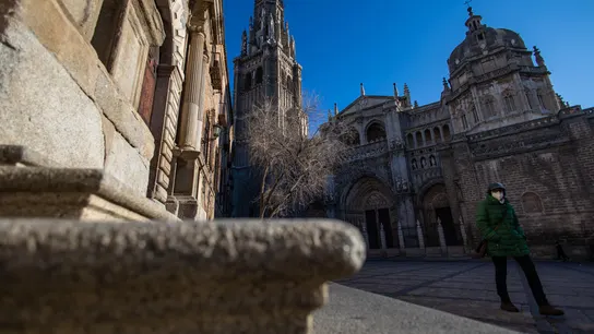 Una persona abrigada camina por una calle de Toledo Una persona abrigada camina por una calle de Toledo