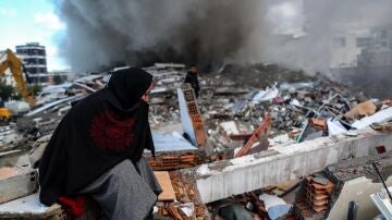 Una mujer busca entre los escombros de un edificio en el distrito de Hatay, Turquía