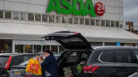 Mujer introduciendo las bolsas de la compra en su vehículo Mujer introduciendo las bolsas de la compra en su vehículo