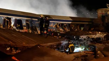 Los bomberos trabajan para sacar a los pasajeros de los trenes después de una colisión cerca de la ciudad de Larissa, Grecia.