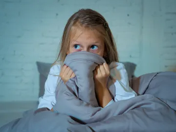 Niña en la cama después de una pesadilla Niña en la cama después de una pesadilla