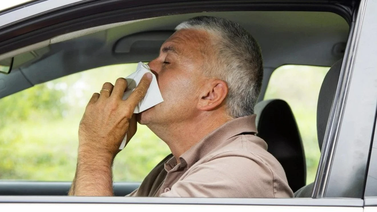 Un hombre se suena en el coche