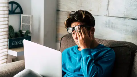 Joven cansado mirando el portátil Joven cansado mirando el portátil