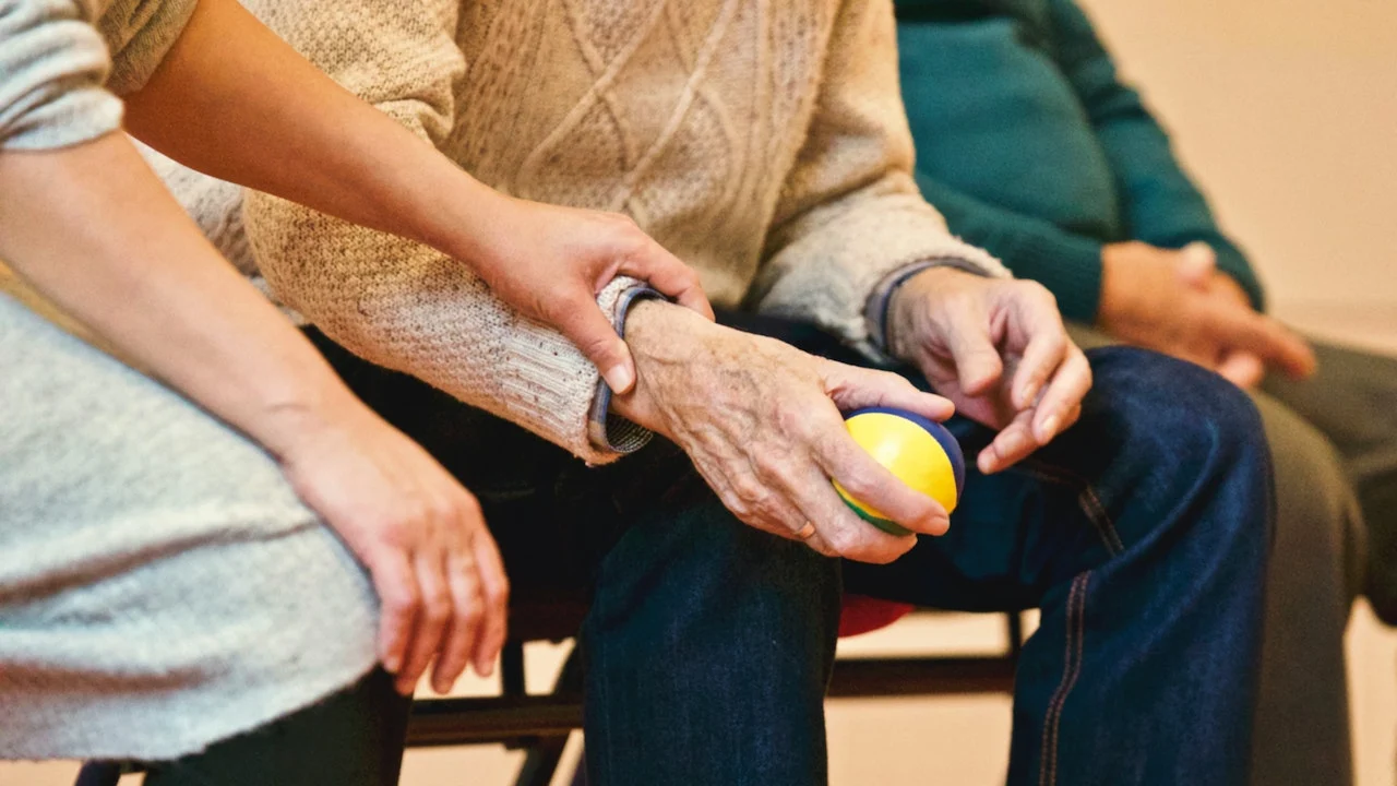 Imagen de archivo de un familiar dando la mano a un anciano en una residencia