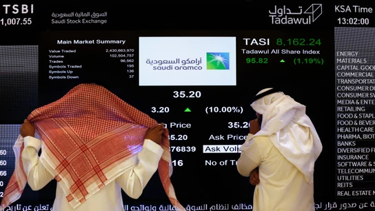 Dos personas observan la cotización en Bolsa de Aramco Dos personas observan la cotización en Bolsa de Aramco