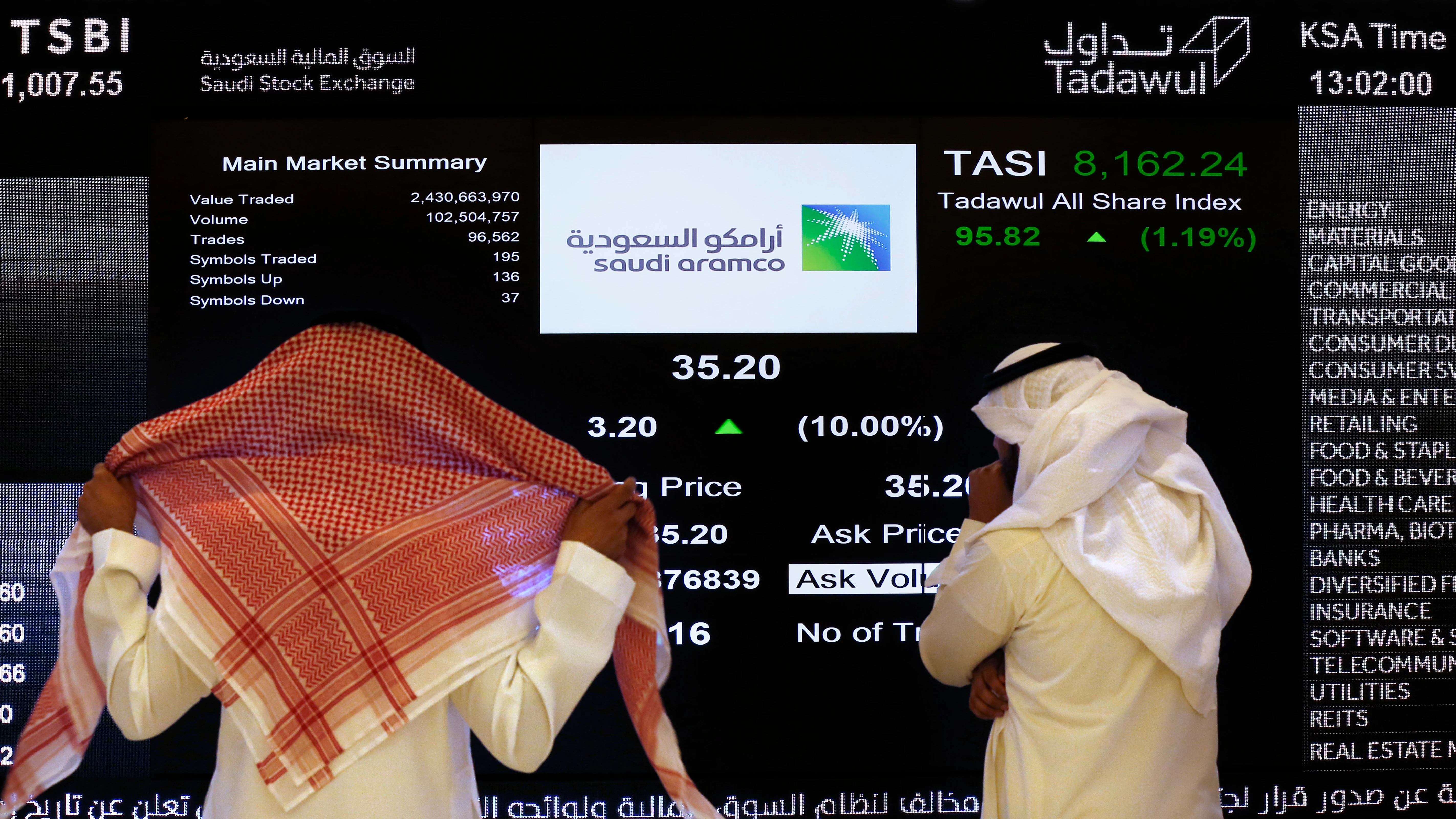 Dos personas observan la cotización en Bolsa de Aramco