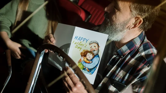 Un padre recibiendo una tarjeta de felicitación por el Día del Padre Un padre recibiendo una tarjeta de felicitación por el Día del Padre