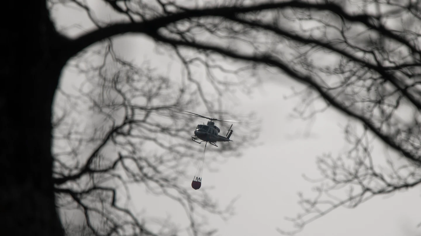 Un helicóptero transporta agua durante los trabajos de extinción de un incendio forestal en la localidad cántabra de Los Corrales de Buelna. Un helicóptero transporta agua durante los trabajos de extinción de un incendio forestal en la localidad cántabra de Los Corrales de Buelna.