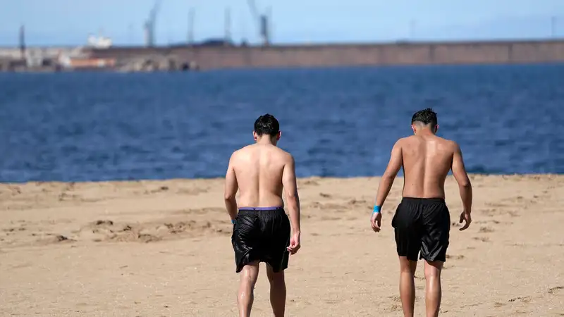 Dos jóvenes tras darse un baño en la playa de Poniente, en Gijón